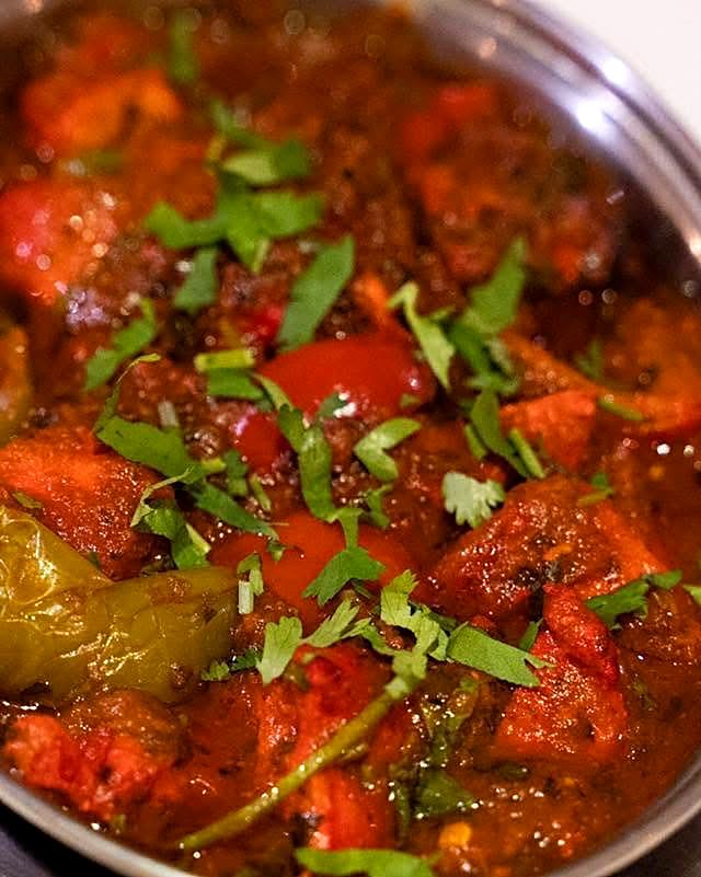 A rich red karahi curry topped with coriander at Buraq
